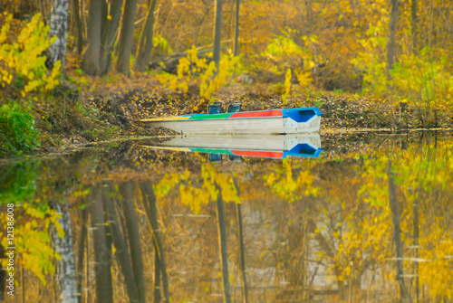 Colorful boat at autumn pond in yellow forest