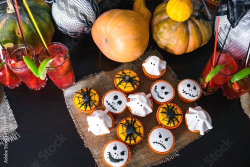 Group of halloween cupcakes with pumpkin and cocktails background