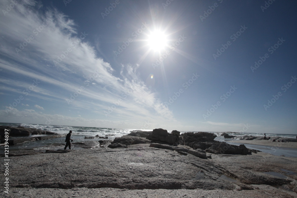 alone man on a rocky beach with bright sun