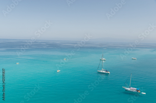 Small boats on the crystal clear sea near the town of Tropea region Calabria - Italy 