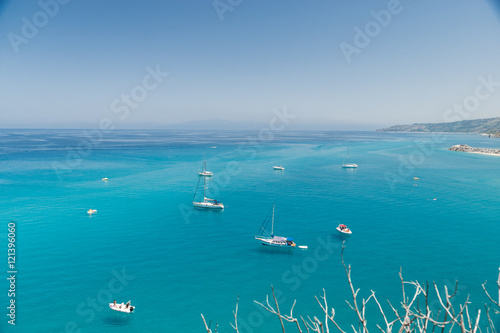 Small boats on the crystal clear sea near the town of Tropea region Calabria - Italy 