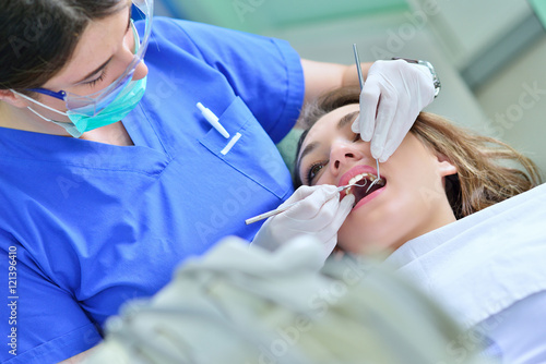 A pretty young woman with a bright  white smile lying in the dentist s chair having a checkup