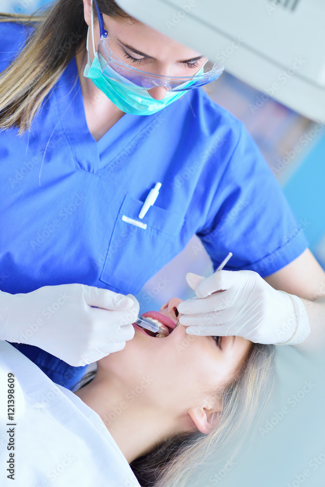 A pretty young woman with a bright, white smile lying in the dentist's chair having a checkup A pretty young woman with a bright, white smile lying in the dentist's chair having a checkup