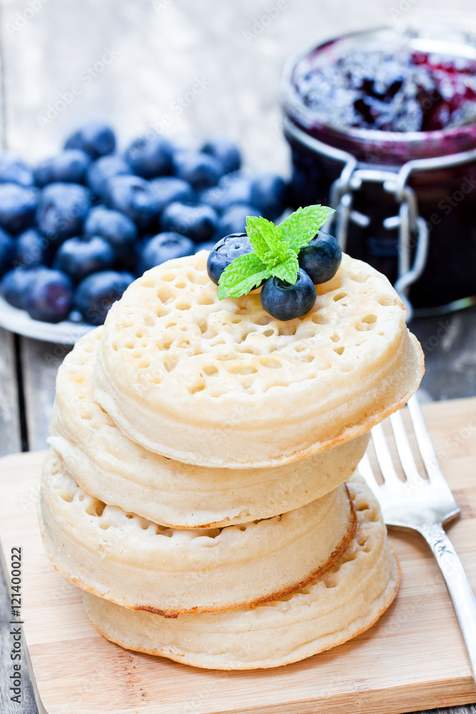 Hot toasted crumpets on the wooden table with blueberries and j Hot toasted crumpets on the wooden table with blueberries and j