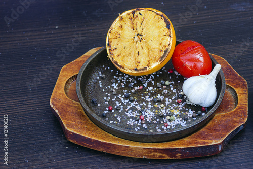 Grilled lemon, tomato and garlic with herbs in a cast iron fryin photo