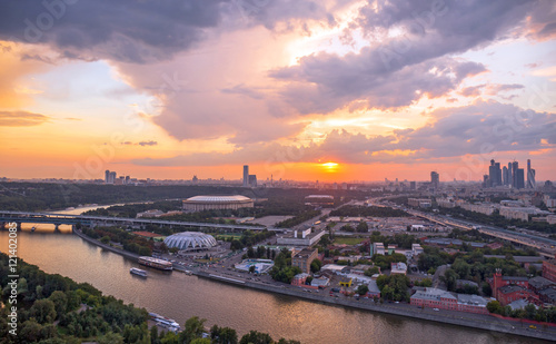 Panoramic view of sunset above Moscow city and cloud reflections in river with traveling boats