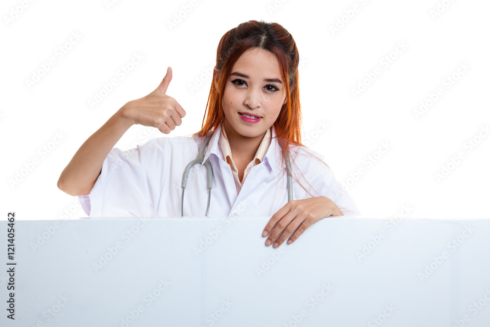Young Asian female doctor show thumbs up behind blank white bil Young Asian female doctor show thumbs up behind blank white bil