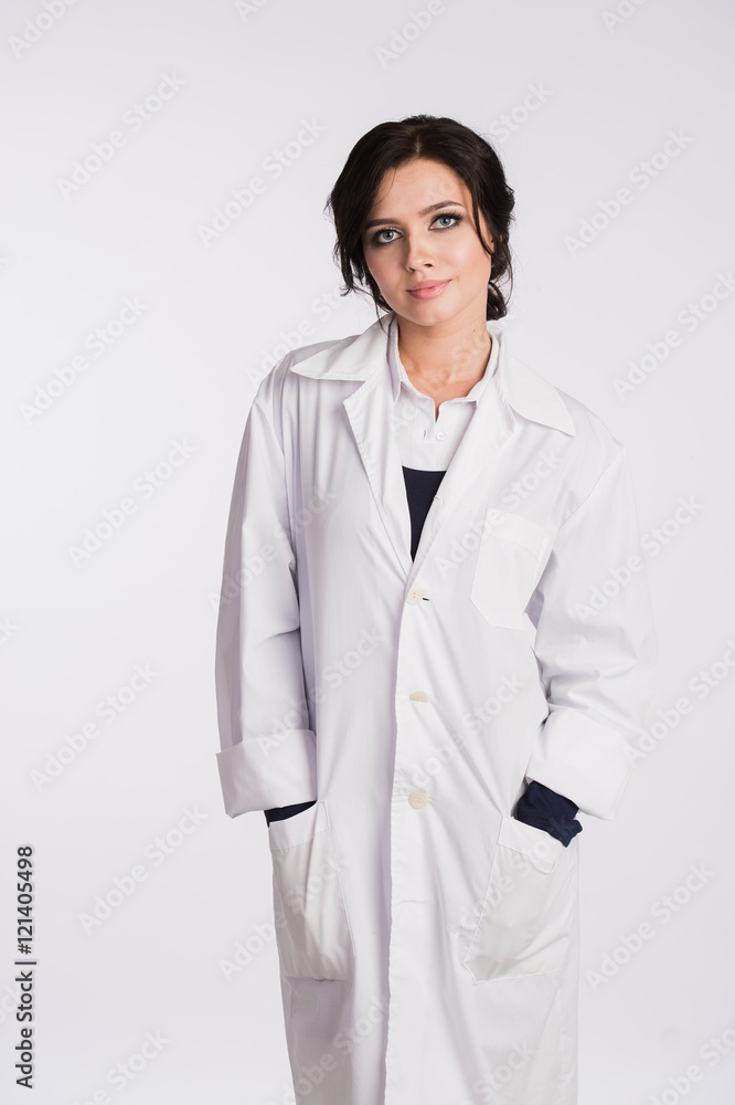 Smiling medical doctor woman with hands in pockets of robe looking at camera isolated on white Smiling medical doctor woman with hands in pockets of robe looking at camera isolated on white
