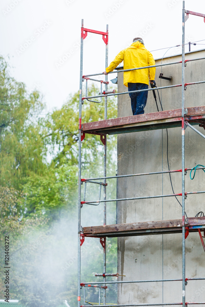 Man cleaning wall. Scaffolding Man cleaning wall. Scaffolding