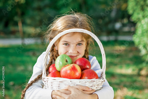 Little girl holding a basket of apples