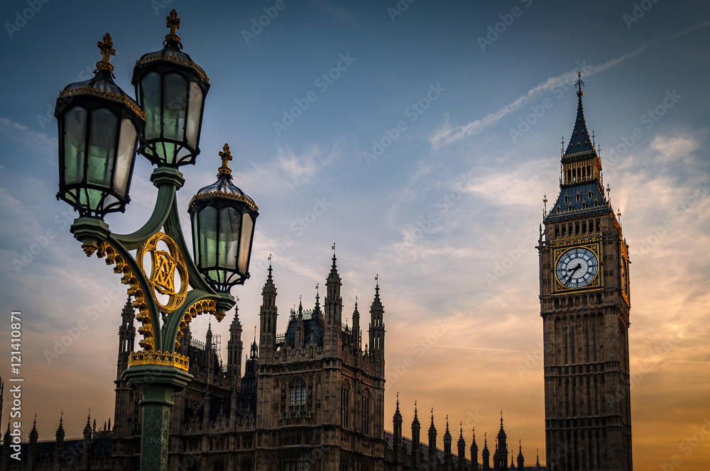Fototapeta premium Big Ben, The Houses of Parliament and a lamppost from the Westminster bridge at sunset on a cloudy summer evening in London, England, UK