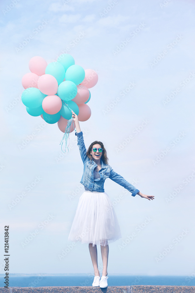 Beautiful young woman with colorful balloons on sea front Beautiful young woman with colorful balloons on sea front