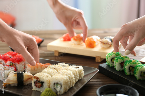 Hands taking delicious sushi on table