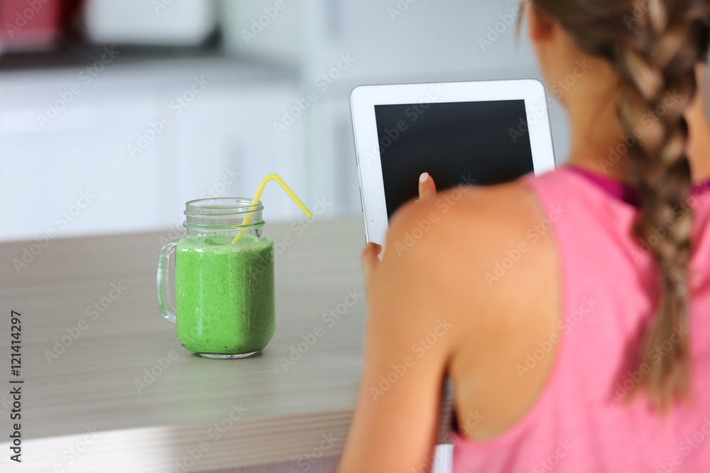 Girl with tablet and smoothie calculating calories on kitchen Girl with tablet and smoothie calculating calories on kitchen