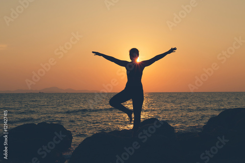 Silhouette woman. she exercise yoga on the rock at beach, At  su