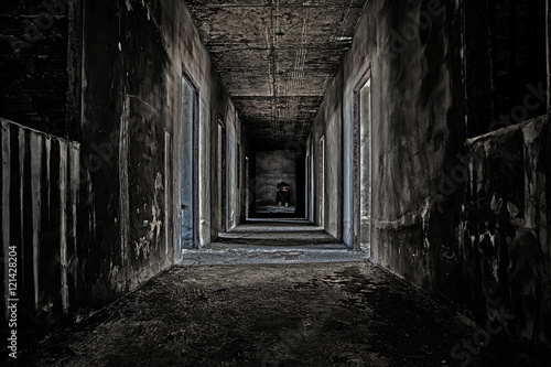 some people sitting in the room at end of scary hallway walkway in abandoned building