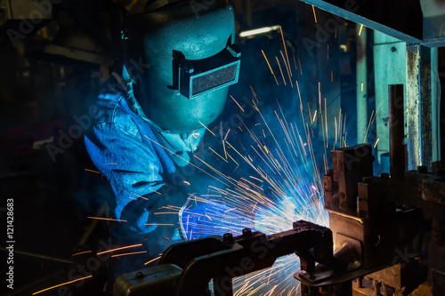 Worker welding automotive part in factory