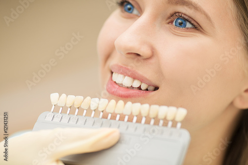 Close up portrait of Young women in dentist chair  Check and select the color of the teeth. Dentist makes the process of treatment in dental clinic office.Dentist
