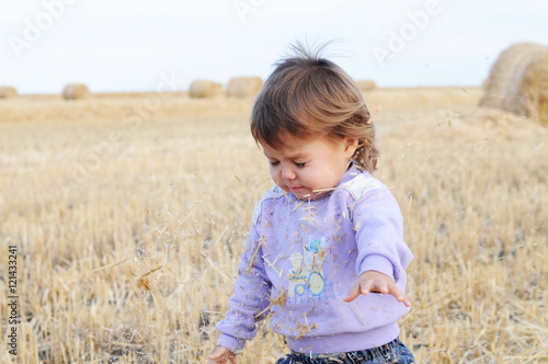 Little girl playing with hay