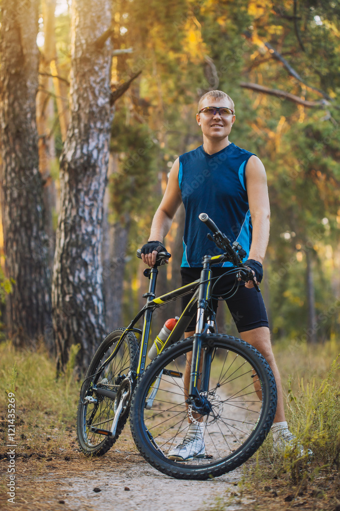 Naklejka premium man cyclist rides forest paths