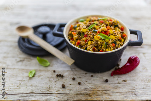 Photos Millet groats with ground beef and vegetables and herbs in a pot on a wooden table