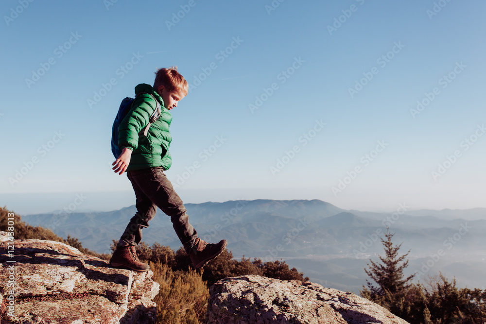 Naklejka premium little boy with backpack hiking in mountains