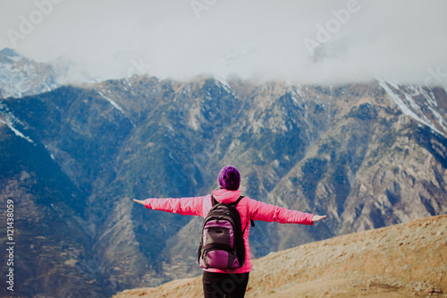 travel concept- happy young woman hiking in snow mountains