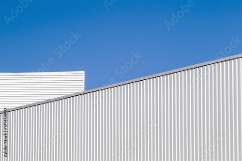 Corrugated sheet metal wall and roof against blue sky. Modern warehouse or storage. Industrial look. Outdoor. Digital background