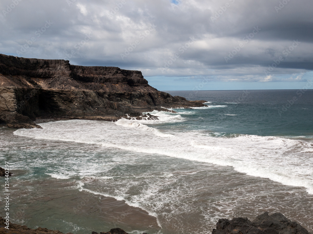 Wave splashing over a rock on the beach of Puertito de los Molinos on Fuerteventura. Canary Island, Spain