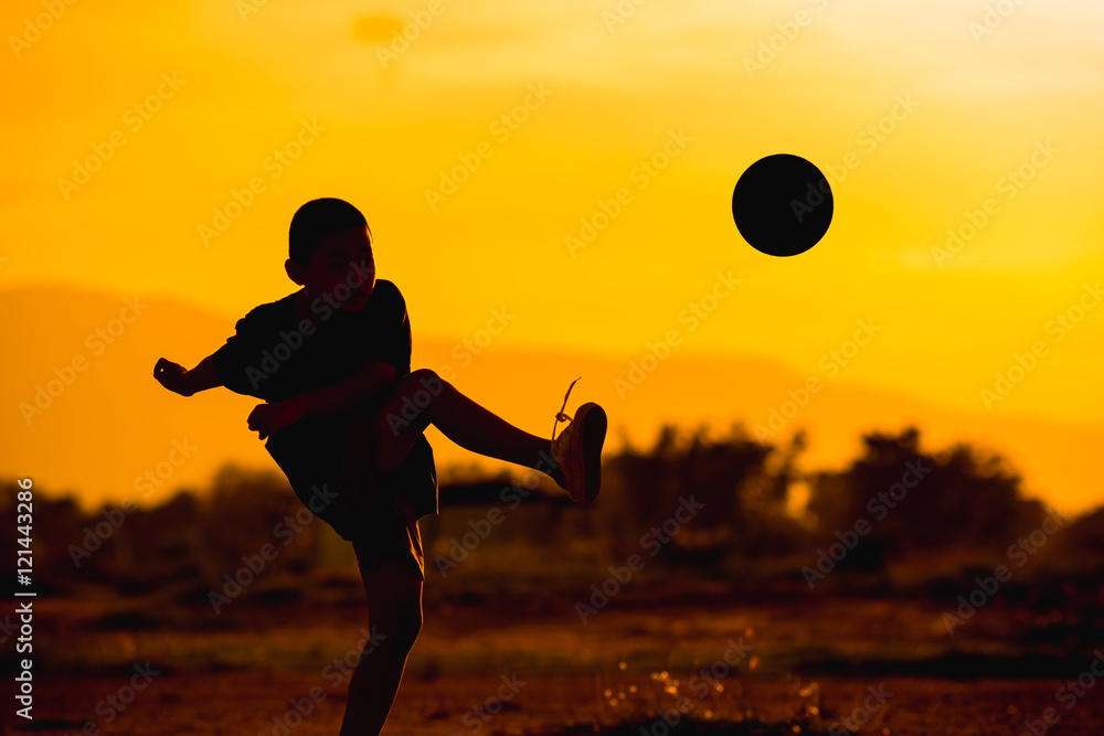 Fototapeta premium boy is playing football in the sunshine day.