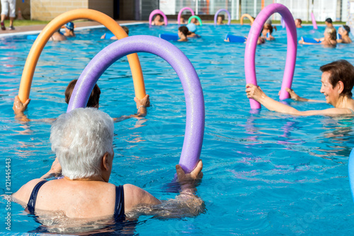 Fototapeta Naklejka Na Ścianę i Meble -  Senior women doing exercise with soft foam noodles in pool.