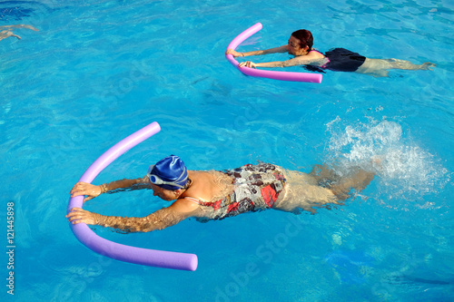 Two senior women doing swimming exercise in pool. photo