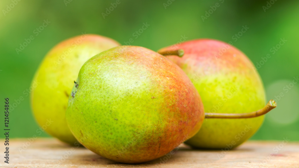 Three ripe organic pears on wooden board, blurred background, selective focus. Three ripe organic pears on wooden board, blurred background, selective focus.