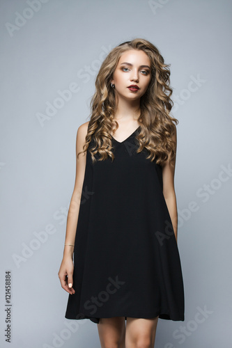 Beautiful girl in a black dress in the studio on a white backgro