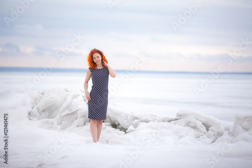 Red-haired girl dressed in a dress in the snow