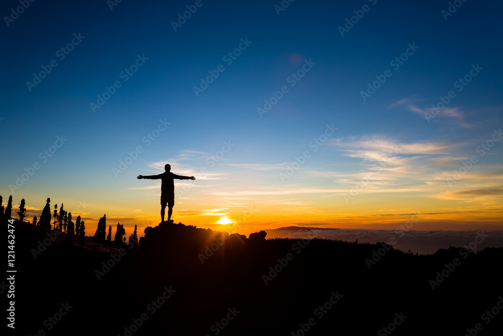 Man with arms outstretched celebrate mountains sunset, inspirational beautiful landscape.