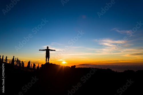 Man with arms outstretched celebrate mountains sunset, inspirational beautiful landscape.