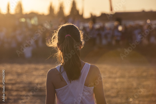 A girl from the back in a golden field.