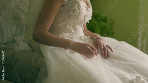 The beautiful amusing bride in a white dress sits on a brown background