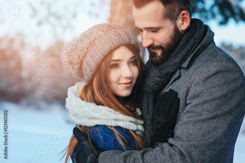 happy loving couple walking in snowy winter forest, spending christmas vacation together. Outdoor seasonal activities. Lifestyle capture.