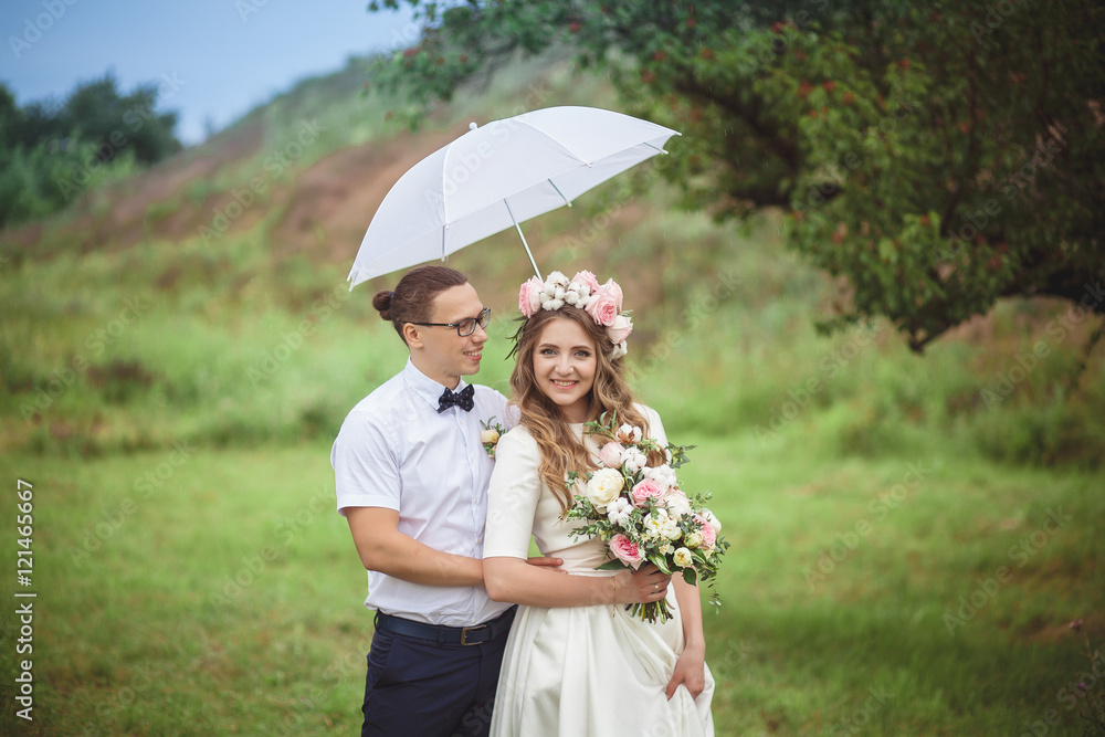 Bride and groom smile hugging under a white umbrella Bride and groom smile hugging under a white umbrella