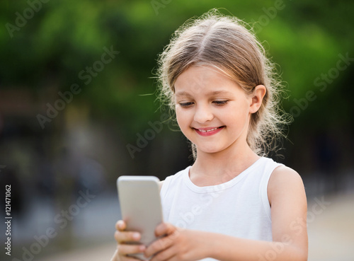 Portrait of smiling girl playing with mobile phone