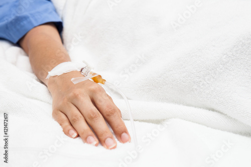 Closeup saline water line at the hand of patient on bed in hospi