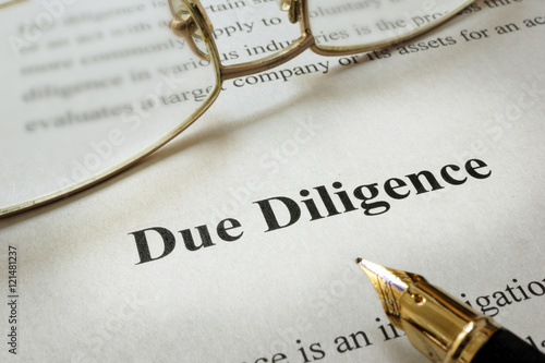Page of paper with words Due Diligence and glasses.