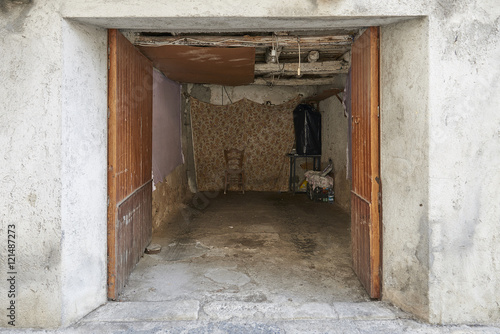 misera povera abitazione con porta aperta e sedia sul fondo