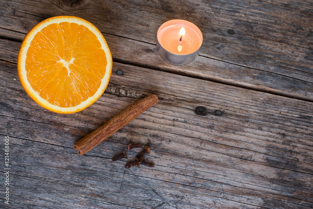 Weihnachtshintergrund: Orange, Zimt, Nelken und Teelicht auf Holzuntergrund Weihnachtshintergrund: Orange, Zimt, Nelken und Teelicht auf Holzuntergrund