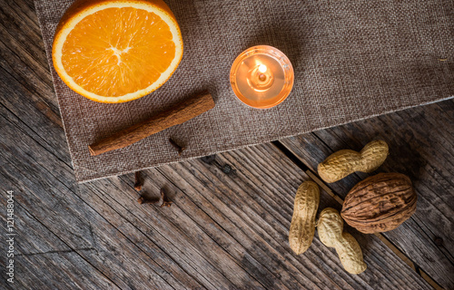 Weihnachtshintergrund: Orange, Zimt, Nüsse, Nelken und Teelicht auf Holzuntergrund