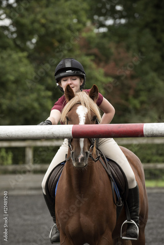 Young rider showing a pony a high pole on a jump - September 2016 - Girl riding a Chestnut pony showing the animal the height of the top pole on a fence