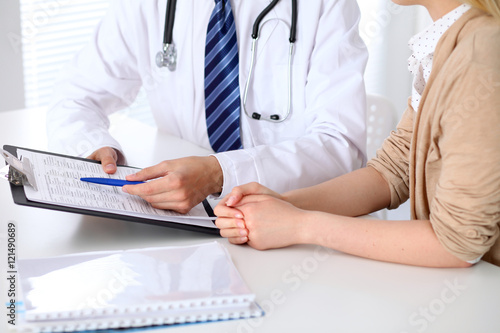 Close-up of a doctor man  holding application form while consulting patient