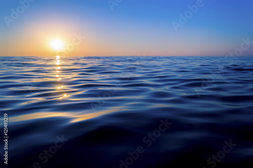 Sunset over the sea. The sun reflected off the waves. Smooth waves. Clear sky